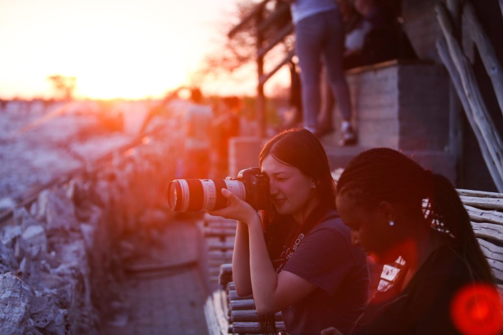 two people with a camera taking pictures of a sunrise