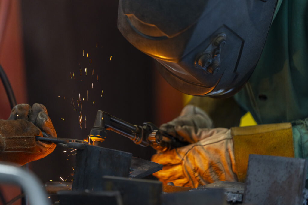 A person welding while wearing gloves and protective face shield. 