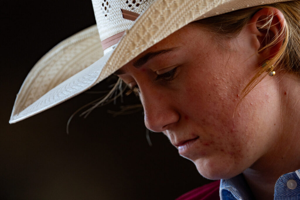 A woman in a cowboy hat looks down