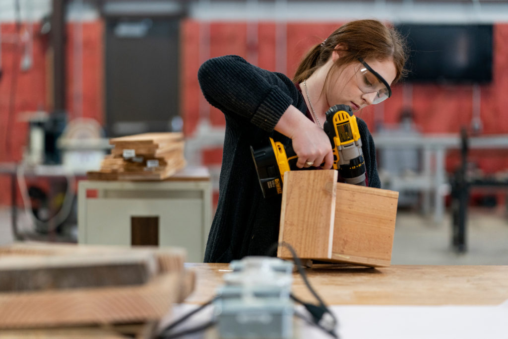 Student using a power drill working in a woodshop