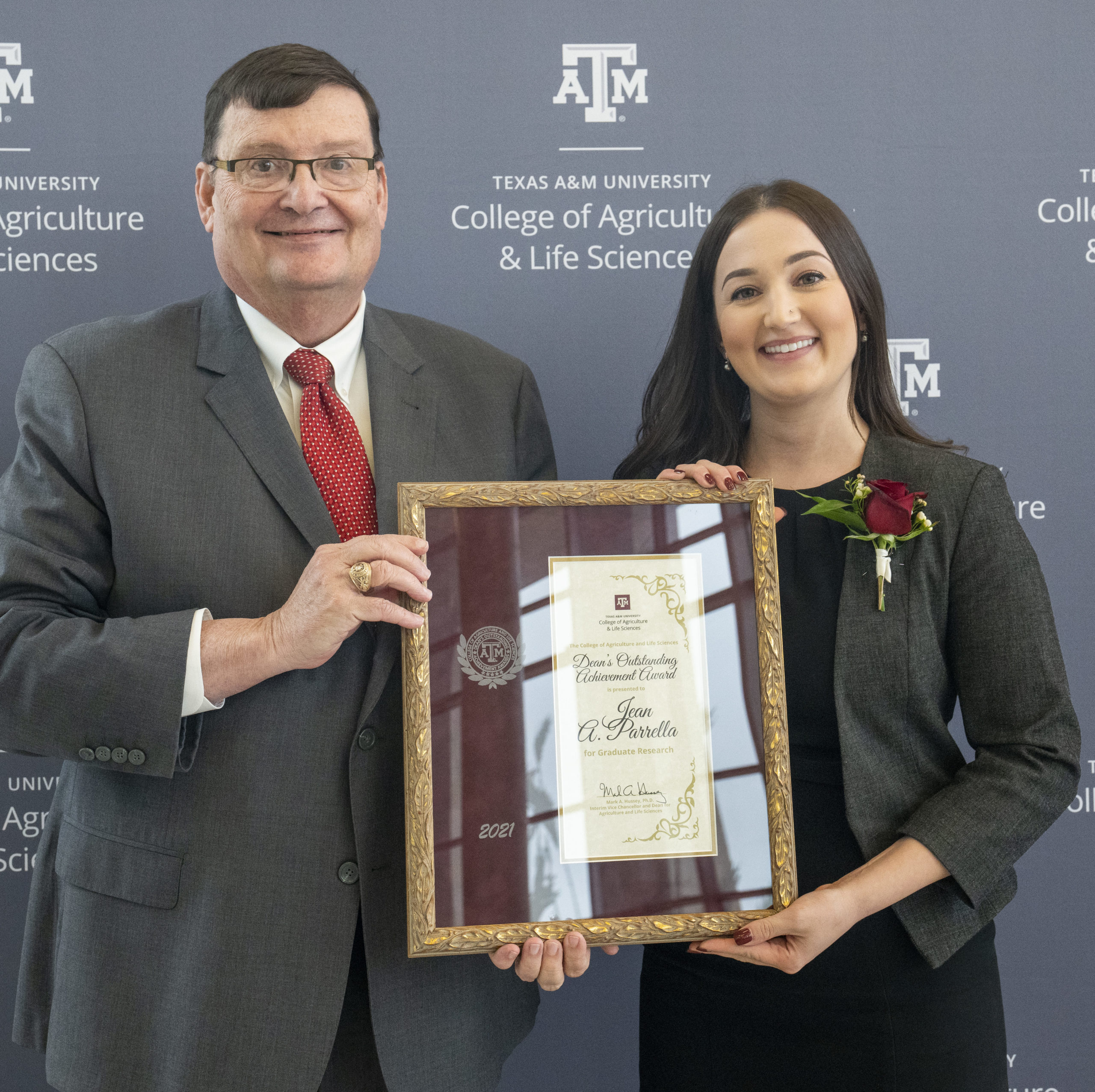 A man and woman holding up a Doctoral degree encased in a wooden and glass frame