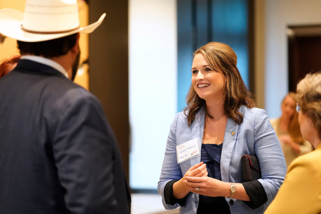 Student smiling while talking to a group of people