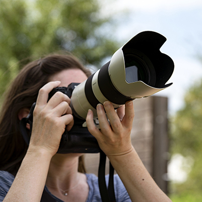 woman using a camera with a large lens