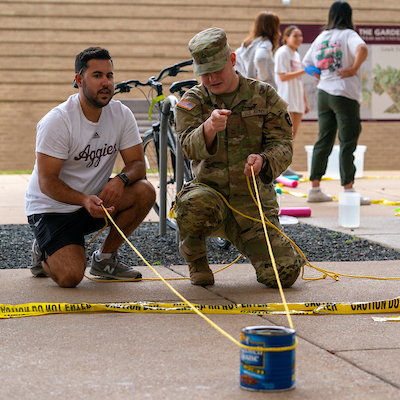 Two students holding a yellow rope and working together on a project