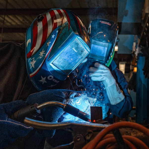 two students in protective gear welding